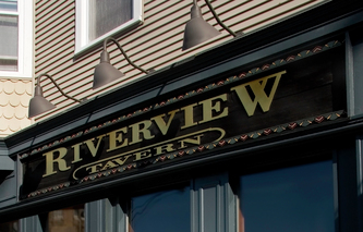 Image shows the wooden facade sign for the Riverview Tavern in Roscoe Village Chicago, IL